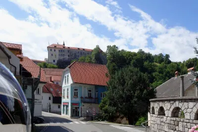 Einfahrt in die Stadt Skofja Loka. Über der Stadt ragt hoch die Burg auf. Einfahrt mit dem Motorrad in die Stadt. Burg hoch über der Stadt