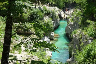 Bei einer geschätzten Wassertemperatur im einstelligen Bereich ziehen es die meisten Badegäste vor, ein Sonnenbad in fotogener Umgebung zu nehmen. Soča, türkisfarbenes Wasser inmitten schroffer Felsen, auf den Felsen Badegäste und Sonnenanbeter