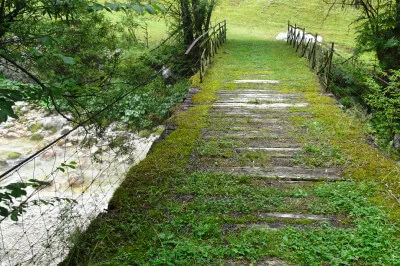 Eine alte Brücke führt über den Fluss, der tausend Gesichter hat. Mal breit und geheimnisvoll dampfend, dann wieder eng gedrängt in einem felsigen Bett. Alte Brücke, aus Eisen und Holz, mit Moos und Farnen, der Fluss dampft.