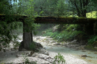 Alte Brücke, aus Eisen und Holz, mit Moos und Farnen, der Fluss dampft.