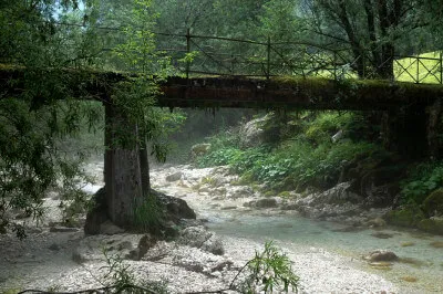 Eine alte Brücke führt über den Fluss, der tausend Gesichter hat. Mal breit und geheimnisvoll dampfend, dann wieder eng gedrängt in einem felsigen Bett. Alte Brücke, aus Eisen und Holz, mit Moos und Farnen, der Fluss dampft.