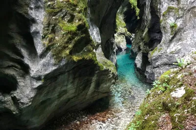 Im Laufe der Jahrtausende formte das Wasser der beiden Flüsse Tolminka und Zadlaščica eine pittoreske Schlucht. Schmale Wanderwege und unzählige Stufen führen die Besucher hindurch. Schlucht mit Felsen und türkisblauem Wasser, pittoresk