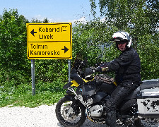 Motorradfahrer steht vor Straßenschild