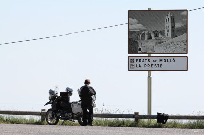 Motorrad steht vor einer kleinen Holzleitplanke und der Fahrer genießt das Panorama auf dem Coll d'Ares