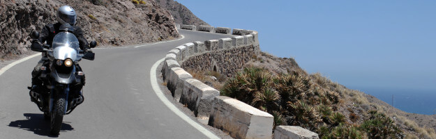Motorrad fährt auf geschwungener Küstenstraße mit Meerblick am Cabo de Gata