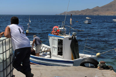 Fischer steht vor Fischerboot am Hafen in La Isleta del Moro