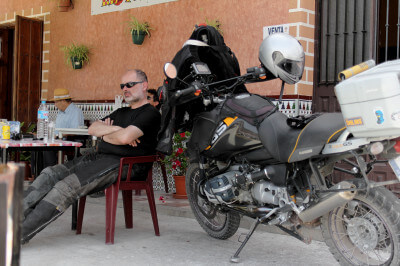 Motorradfahrer sitzt neben seinem Motorrad in einer Tapasbar