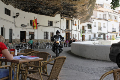 Motorrad fährt durch Dorf mit Felsüberhängen