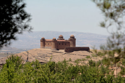 Ein backsteinfarbiges Castell erhebt sich im Hintergrund auf einem Hügel
