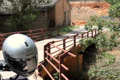Motorrad steht vor einer alten Brücke mit Metallgeländer bei einer Pause