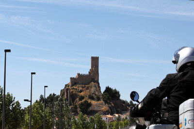 Motorradfahrer blickt auf das hochstrebene Castillo de Almansa