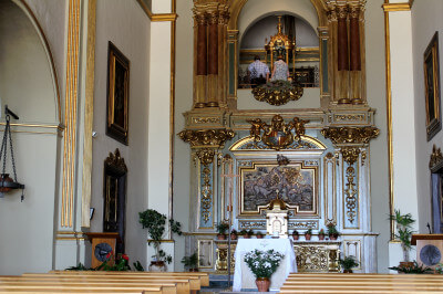 Blick auf den Altar über Kirchenbänke hinweg in der Kirche Santuari de Queralt