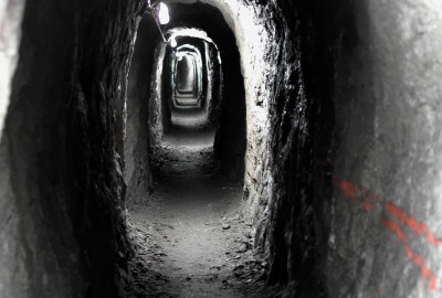 Blick in den beleuchteten naturbelassenen 63 m langen Fußgänger-Tunnel durch den Fels