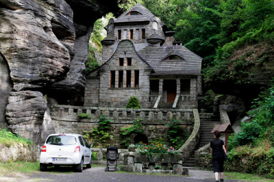 Ein altes Haus eingebaut zwischen Felsen mit Auto davor in Hrensko