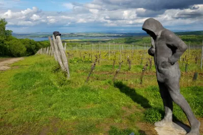Statue des Heiligen Leonhard, des Schutzpatrons der Bauern, entfernt leuchtet das Wasser der Neumühler Stauseen.
