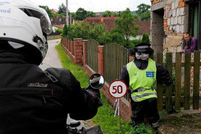 Puppe als Polizist verkleidet am Gartenzaun eines Hauses mit Schild für Geschwindigkeitsbegrenzung 50