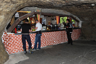 Mehrere Personen stehen an der Bar am Tresen in der Bikerhöhle Pekelné Doly