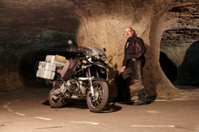 Motorradfahrer steht mit Motorrad in einer Höhle, der Pekelne Doly