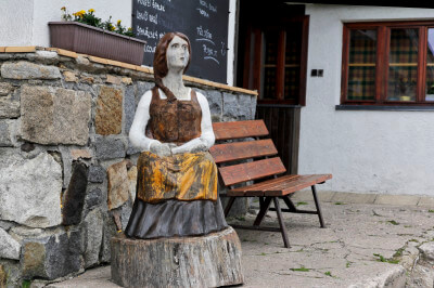 Holzfigur auf einem Holzblock vor dem Eingang zur Berghütte Moravska Bouda
