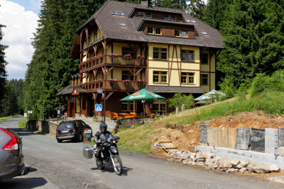 Motorrad fährt auf Straße an einem Haus vorbei im Böhmerwald