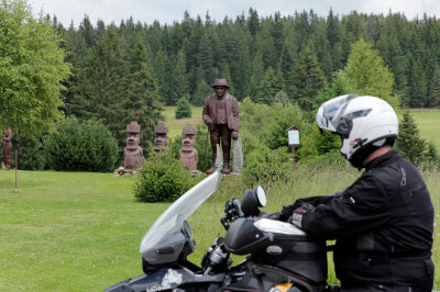 Motorrad steht vor der Holzfigur des Rankl Sepp