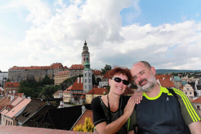 Zwei Personen sitzen auf Bank und im Hintergrund die Burg Ceský Krumlov