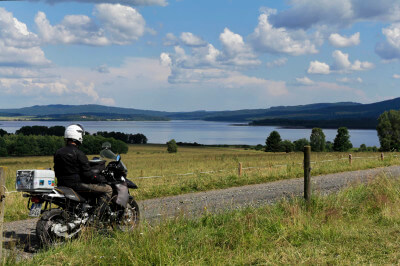 Motorrad steht auf Straße mit einem Panoramablick über den Lipno-Stausee