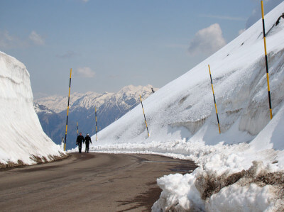 Personen laufen auf der Straßen am Jaufenpass zwischen Schnee