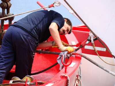 Ein Matrose kontrolliert ein Rettungsboot auf der Fähre
