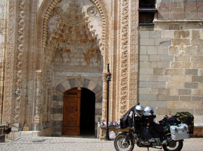 Motorrad steht vor einem mit reich verzierten Ornamenten besetztes Portal am Eingang der Esrefoglu-Moschee