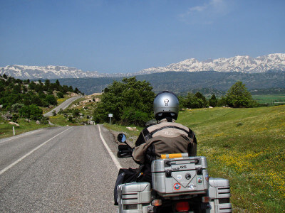 Motorrad steht auf Straße und im Hintergrund schneebedeckte Berge
