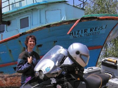 Ein blaues Boot liegt hinter einem Motorrad auf dem Trockenen
