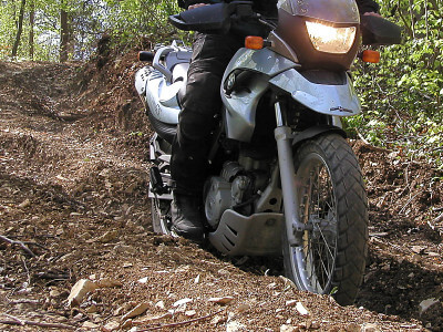 Motorrad fährt einen steilen unbefestigten Waldweg