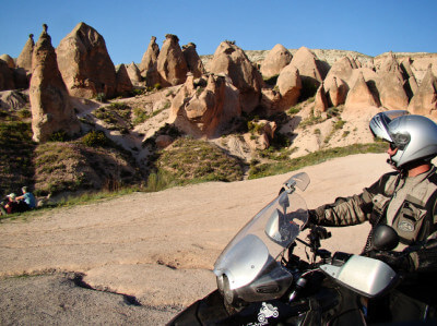Motorrad steht vor spitz zulaufenden Felsenformationen in Kappadokien