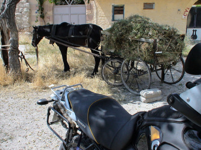Ein Eselfuhrwerk und ein Motorrad stehen im Schatten
