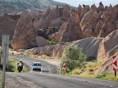 Motorrad fährt auf Straße den Berg vor atemberaubender Kulisse Kappadokiens hinauf