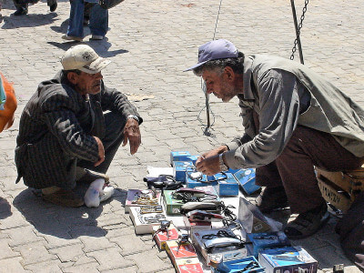 Straßenhändler mit Schermaschinen sitzt im Gespräch mit Kunden