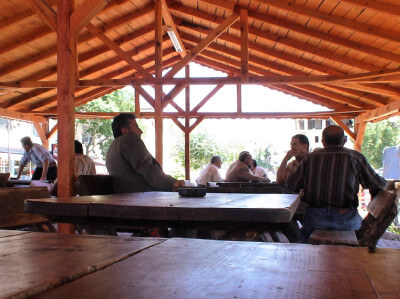 Männer sitzen in überdachter Holzhütte zusammen beim Teetrinken