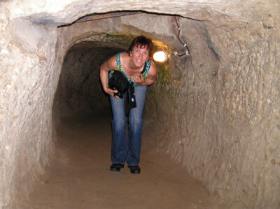  Frau steht gebückt in der unterirdischen Stadt in einem Gang in Derinkuyu