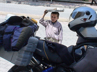 Junge mit Tablet mit Sesamkringel auf dem Kopf möchte verkaufen hinter dem Motorrad