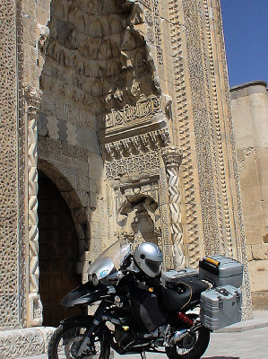 Motorrad steht vor imposantem hochstrebenden und reich verziertem Eingang zur Karawanserei in Sultanhani